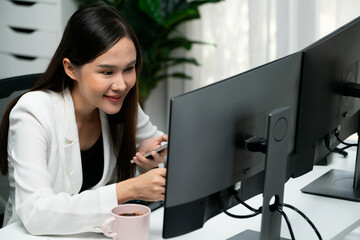 Fototapeta na wymiar Smiling young Asian businesswoman searching marketing online strategy using smartphone to analyze digit report compare with pc in business analysis to make sales target in trader business. Stratagem.