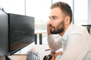 Crypto trader sits at his workplace in front of a monitor with charts.