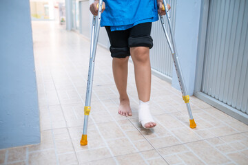 Medical care patient walking using crutches to support her injured ankle sprain, in the hospital...