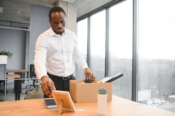 Young african man fired holding box with personal items at business office