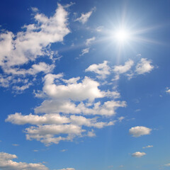 Bright sun on blue cloudy sky. - 784676677