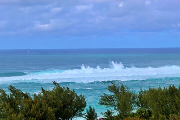 Waves crash against a rocky barrier near a Caribbean coastline