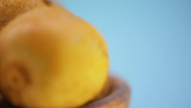 Seamless circular motion: several ripe kiwi in a plate on a blue background.