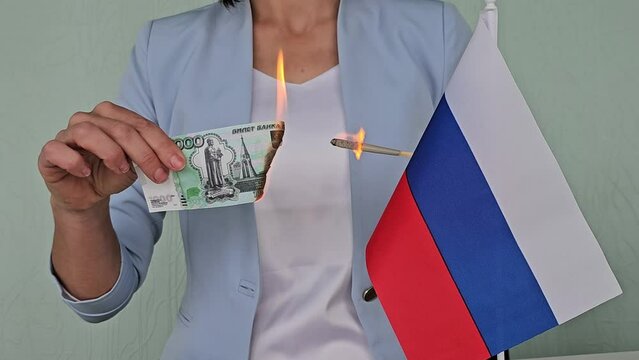 Businesswoman burns a banknote of Russian rubles and with flag of Russia. Economic sanctions war and economy