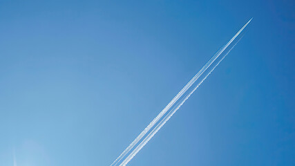 airplane tracks in the air, blue sky background, plane tracks in the sky