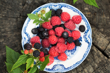 Raspberries and wild blackberries on a vintage plate
