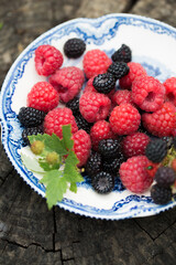 Raspberries and wild blackberries on a vintage plate