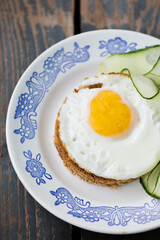 A fried egg on a piece of bread with a cucumber