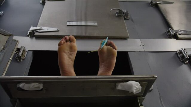 Hanbdheld tilt up to feet of a corpse in a morgue