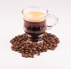 cup of espresso coffee with several roasted coffee beans on white background