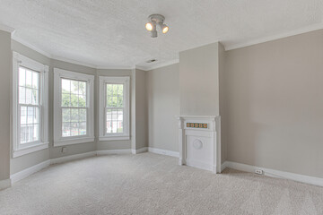 Historic Clean Minimal Empty Room with Neutral Tones, Carpet Flooring, and A White Vintage Fireplace