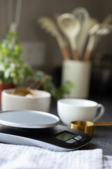 Scales, bowl, measuring spoon, napkin, cup on concrete kitchen counter. Empty space for product. Concept of cooking, weighing ingredients for baking, making and feeding sourdough starter at home