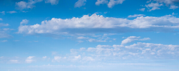 Panoramic view of vivid white clouds against a bright blue summer sky background. The photo features a clear gradient from darker cyan to a light white skyline horizon.