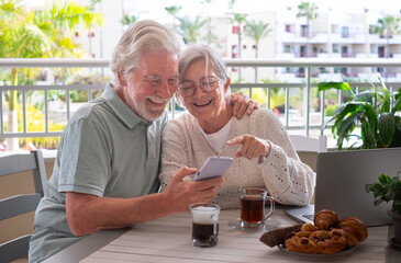 Video call concept. Happy bonding senior retired couple using mobile phone technology for online...