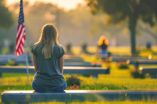 Woman sitting contemplatively at a military cemetery at sunset, symbolizing reflection and sacrifice - Powered by Adobe