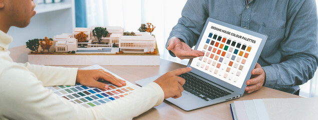 Professional architect presents color selection by using laptop displayed the color while female...