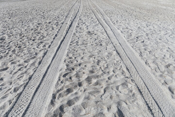 Background of soft beach sand with ATV tire tracks leading off into the distance, creative copy...