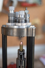 Ammunition reloading process at home. Detail of the manual placement and introduction of the 9mm projectile tip with the press. It is a frustoconical tip of jacketed and copper-plated lead.