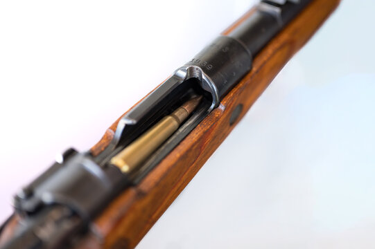 Detail of the introduction of a bullet into the chamber of the Mauser 98 type rifle on a white background