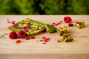 Matcha green tea chocolate with raspberries and dried passion fruit on a wooden surface