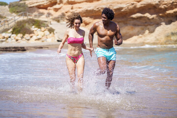 Happy diverse couple jogging in sea water - 784713078