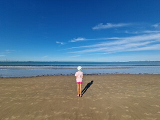 Girl with hat in front of the sea, on a sandy beach. Valdelagrana Beach