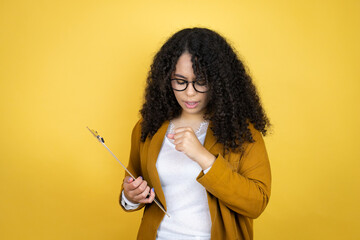 African american business woman with paperwork in hands over yellow background with her hand to her mouth because she's coughing