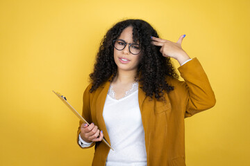 African american business woman with paperwork in hands over yellow background Shooting and killing oneself pointing hand and fingers to head like gun, suicide gesture.
