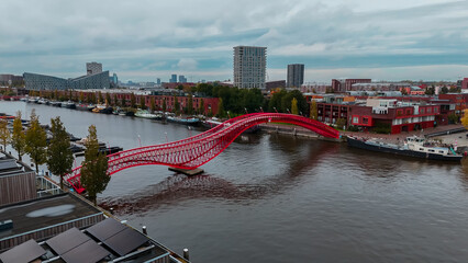 Aerial drone view of modern footbridge Python Bridge at Eastern Docklands neighborhood of Amsterdam...