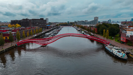 Aerial drone view of modern footbridge Python Bridge at Eastern Docklands neighborhood of Amsterdam...