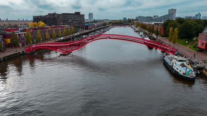 Aerial drone view of modern footbridge Python Bridge at Eastern Docklands neighborhood of Amsterdam...