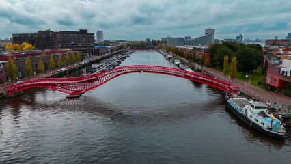 Aerial drone view of modern footbridge Python Bridge at Eastern Docklands neighborhood of Amsterdam...