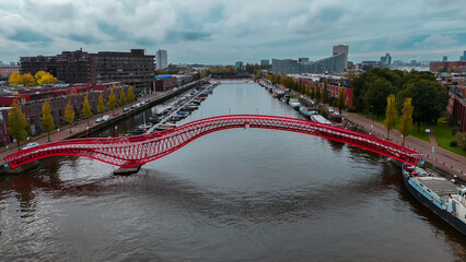 Aerial drone view of modern footbridge Python Bridge at Eastern Docklands neighborhood of Amsterdam...