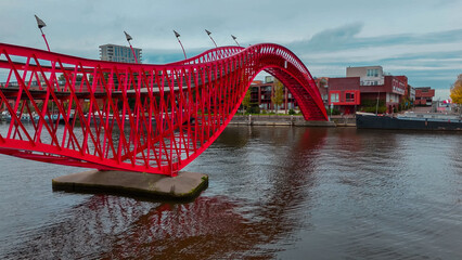 Aerial drone view of modern footbridge Python Bridge at Eastern Docklands neighborhood of Amsterdam...