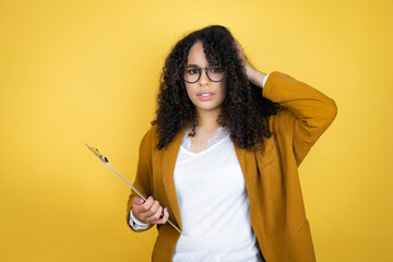 African american business woman with paperwork in hands over yellow background putting one hand on...