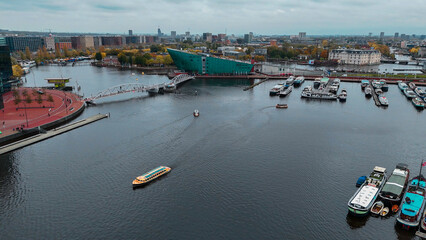 Aerial drone view NEMO museum in Amsterdam autumn cityscape narrow old houses, canals, boats bird's...