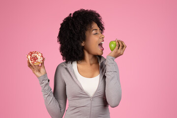 Lady choosing between donut and apple on pink background