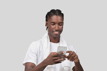 Young man smiling at smartphone screen on white background