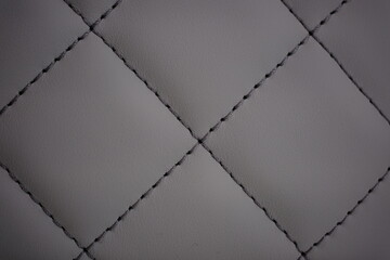 Dark gray contrast thread on natural gray leather car seat close-up - obrazy, fototapety, plakaty