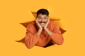 Man with moustache peeking through orange paper