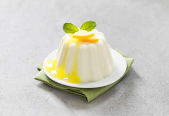 Vegan Lemon cream pudding, Panna Cotta with lemon sauce, on a linen napkin, on a plate. Light grey background. Close-up