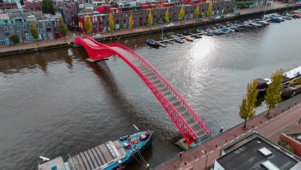 Aerial drone view of modern footbridge Python Bridge at Eastern Docklands neighborhood of Amsterdam...