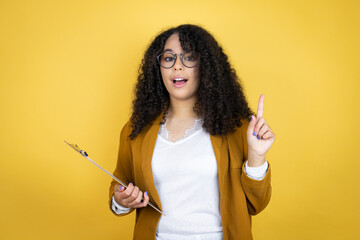 African american business woman with paperwork in hands over yellow background surprised and...
