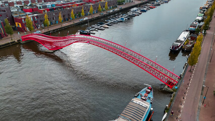 Aerial drone view of modern footbridge Python Bridge at Eastern Docklands neighborhood of Amsterdam...