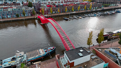 Aerial drone view of modern footbridge Python Bridge at Eastern Docklands neighborhood of Amsterdam...