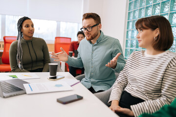 Modern corporate office open space with busy male and female staff employees using laptop computers sitting at work in big modern corporate office. Startup team working together at creative open space