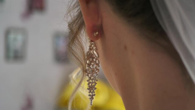Close up rear view of a beautiful woman wearing luxurious dangling earrings. earring in her ear.