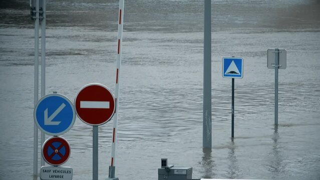 Flooded road with road signs, River Seine in Paris, France. Text in French: except lafarge vehicles