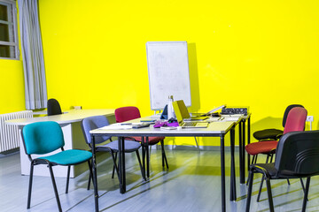 A yellow room with a white board and a table with a white board