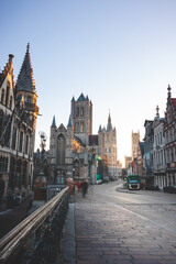 Fototapeta na wymiar Well-known Ghent city centre with a view of the Belfry of Ghent at sunrise, three towers symbolizing this city. The Golden Hour
